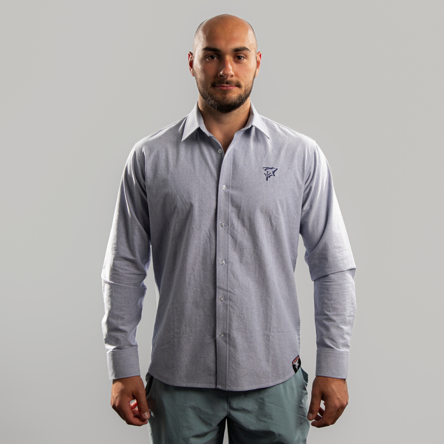Hemd TEAM Hellblaues Hemd mit dezentem Button-Down-Kragen und dunkelblauer Haie-Stickerei (Shark-Logo) auf der linken Brustseite. Getragen von Maxi Glötzl, Frontansicht, vor hellem Hintergrund.
