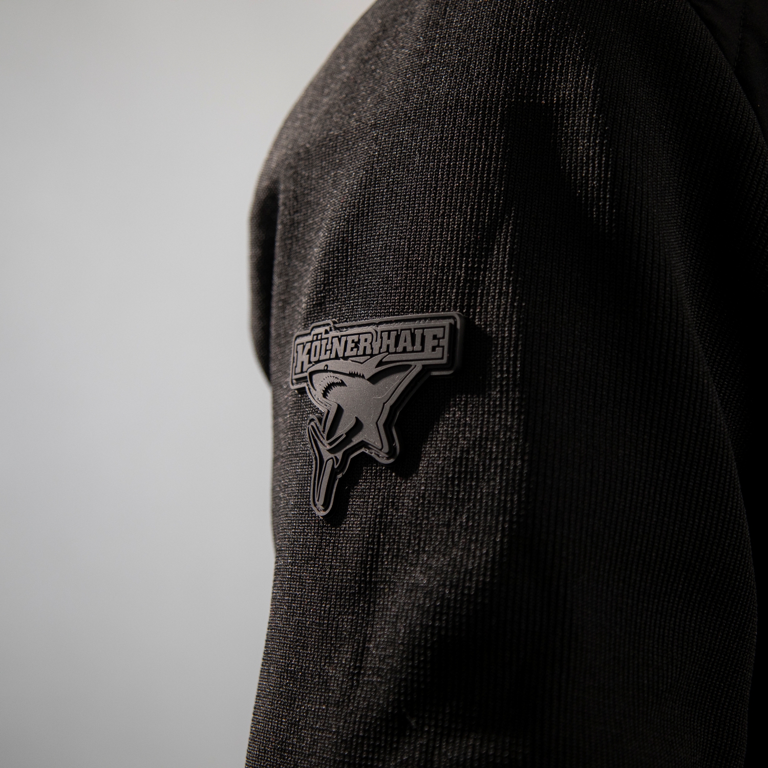 Detailansicht Ton-in-Ton Kölner Haie-Logo als Patch auf rechter Schulter.