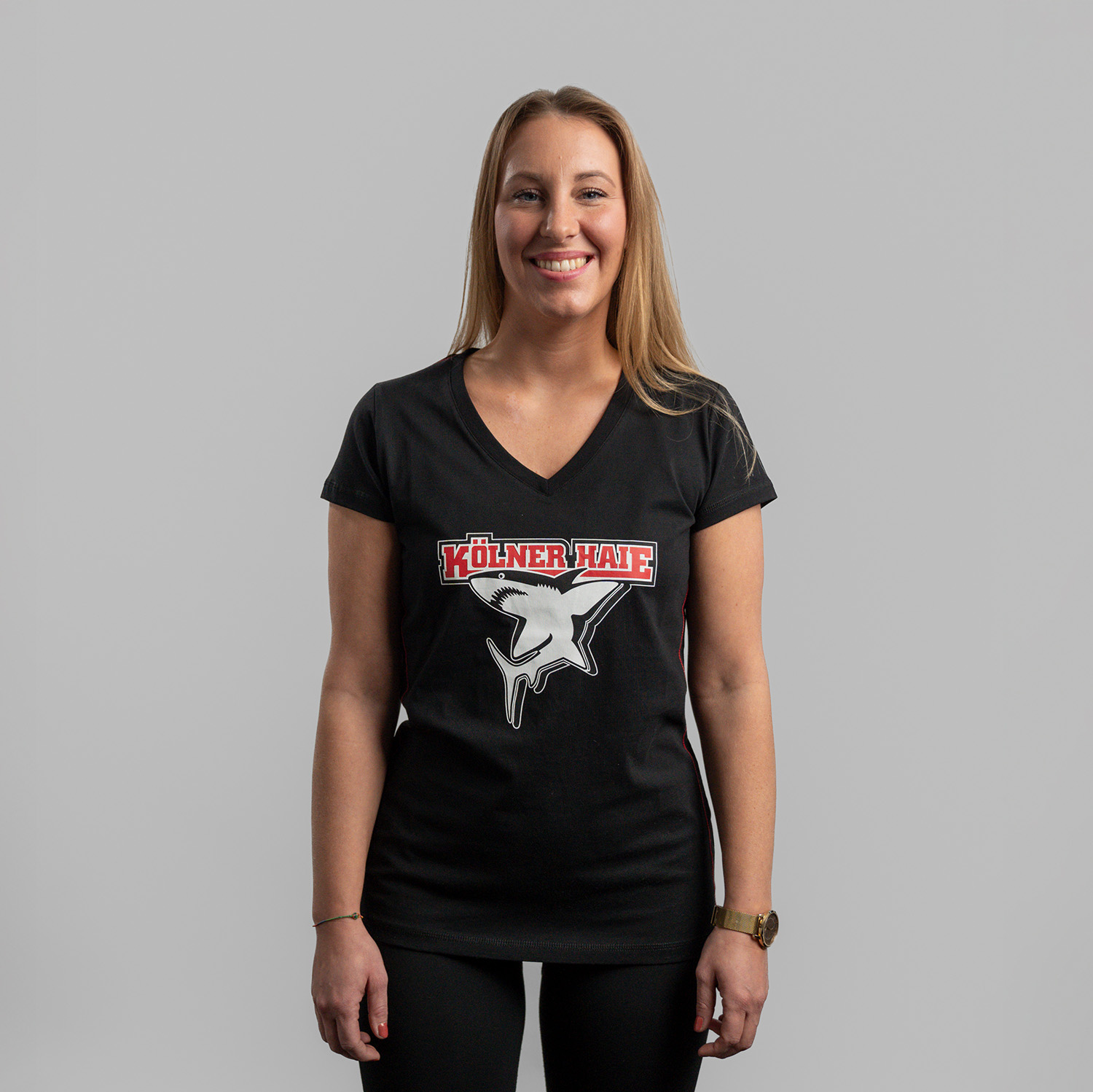 Schwarzes Damen T-Shirt mit großem Frontprint vom Kölner Haie-Logo, getragen von Model, Frontansicht, vor hellem Hintergrund.