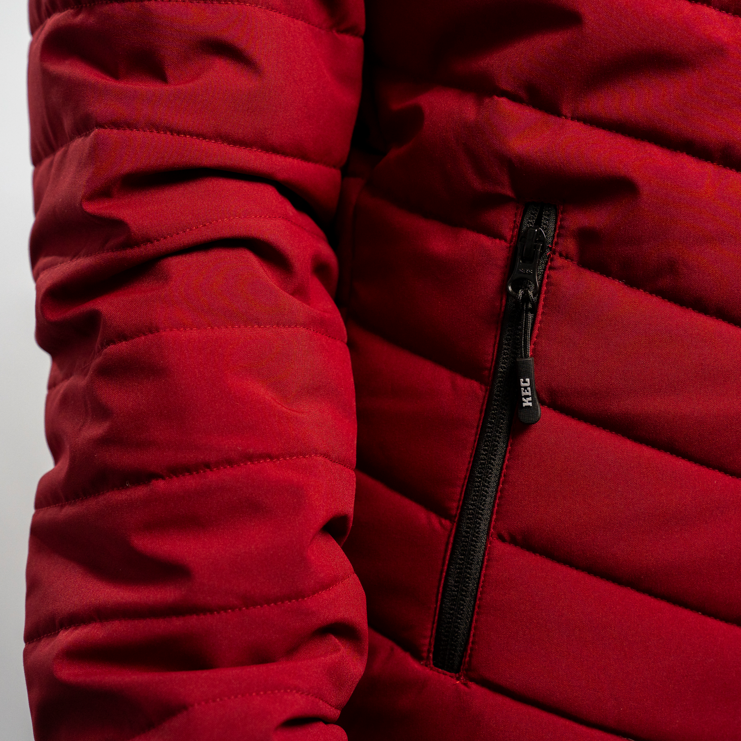 Detailansicht Reißverschluss Eingrifftasche mit schwarzem Zipper und KEC Schriftzug der bordeauxroten Kölner Haie Jacke.