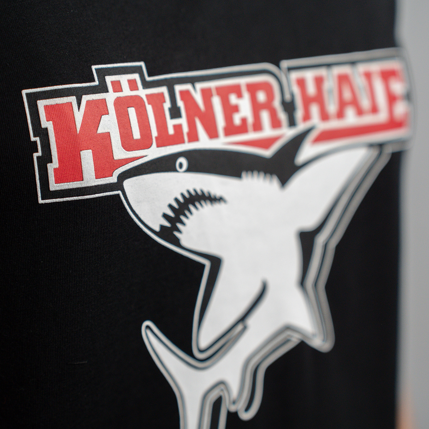 Detailansicht 3D-Druck vom Kölner Haie-Logo auf schwarzem Damen T-Shirt.