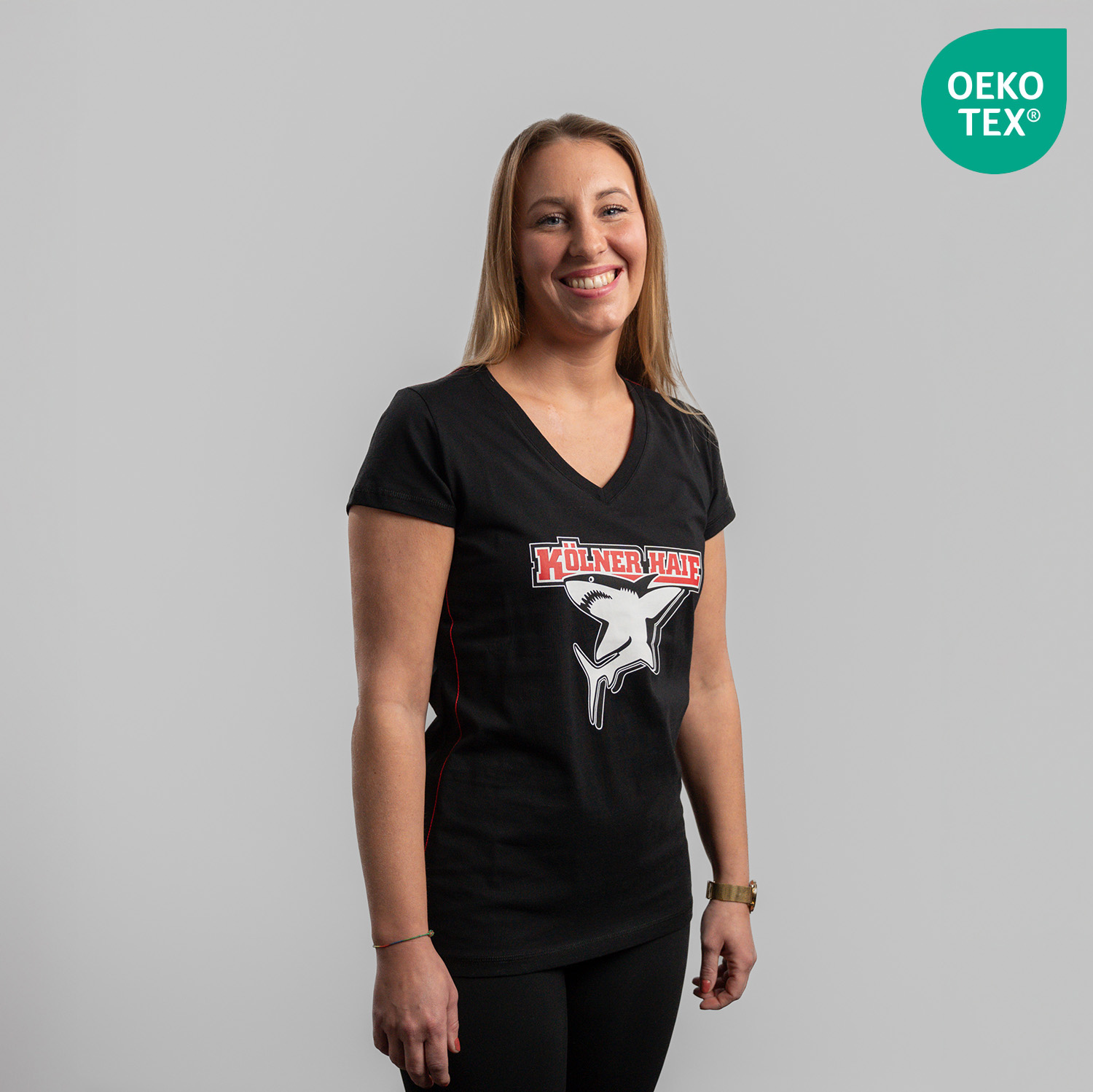 T-Shirt BASIC lady Schwarzes Damen T-Shirt mit großem Frontprint vom Kölner Haie-Logo, getragen von Model, Seitansicht, rechte Schulter vorne, vor hellem Hintergrund.